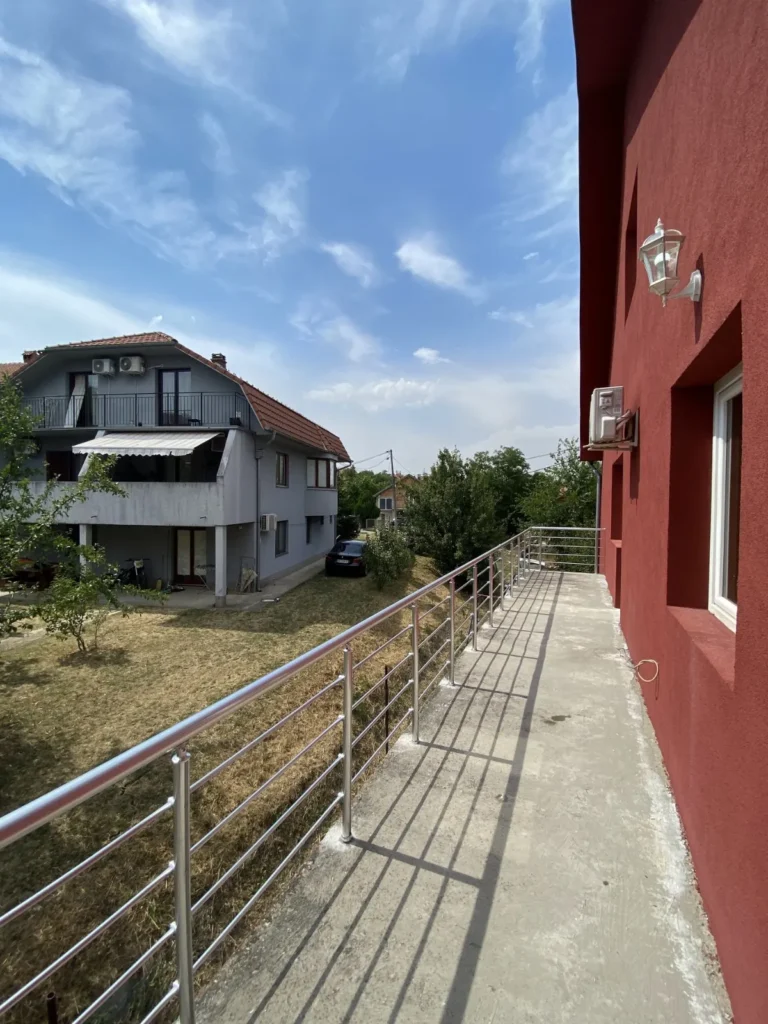 Dugačka aluminijumska ograda uz crvenu fasadu